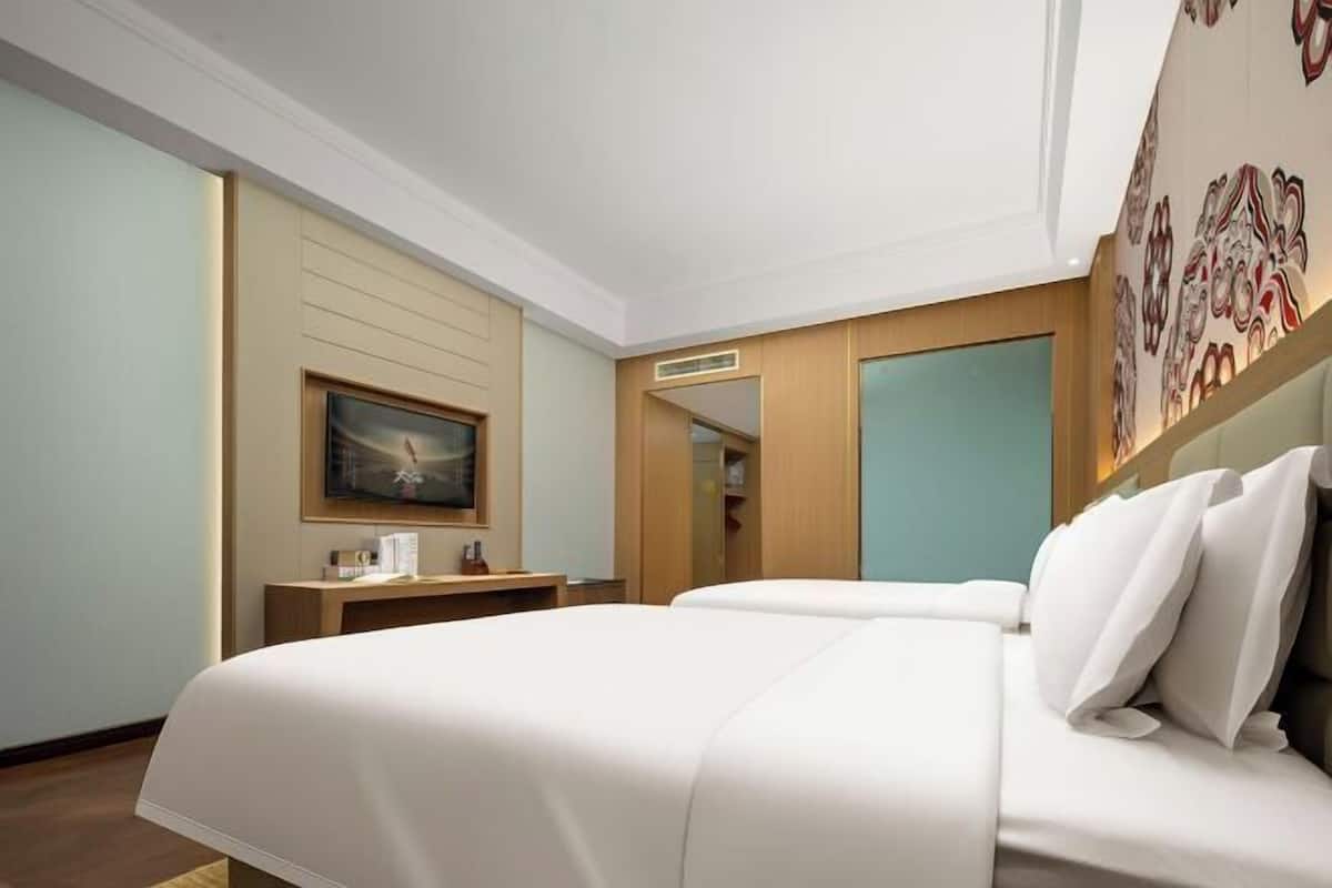 Una habitación de hotel con una cama grande, un escritorio con televisor de pantalla plana y un armario.