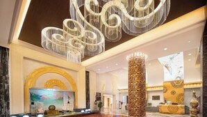 A spacious lobby with a large chandelier, a reception desk, and a decorative column. - Yulin Hotel (Guazhou)