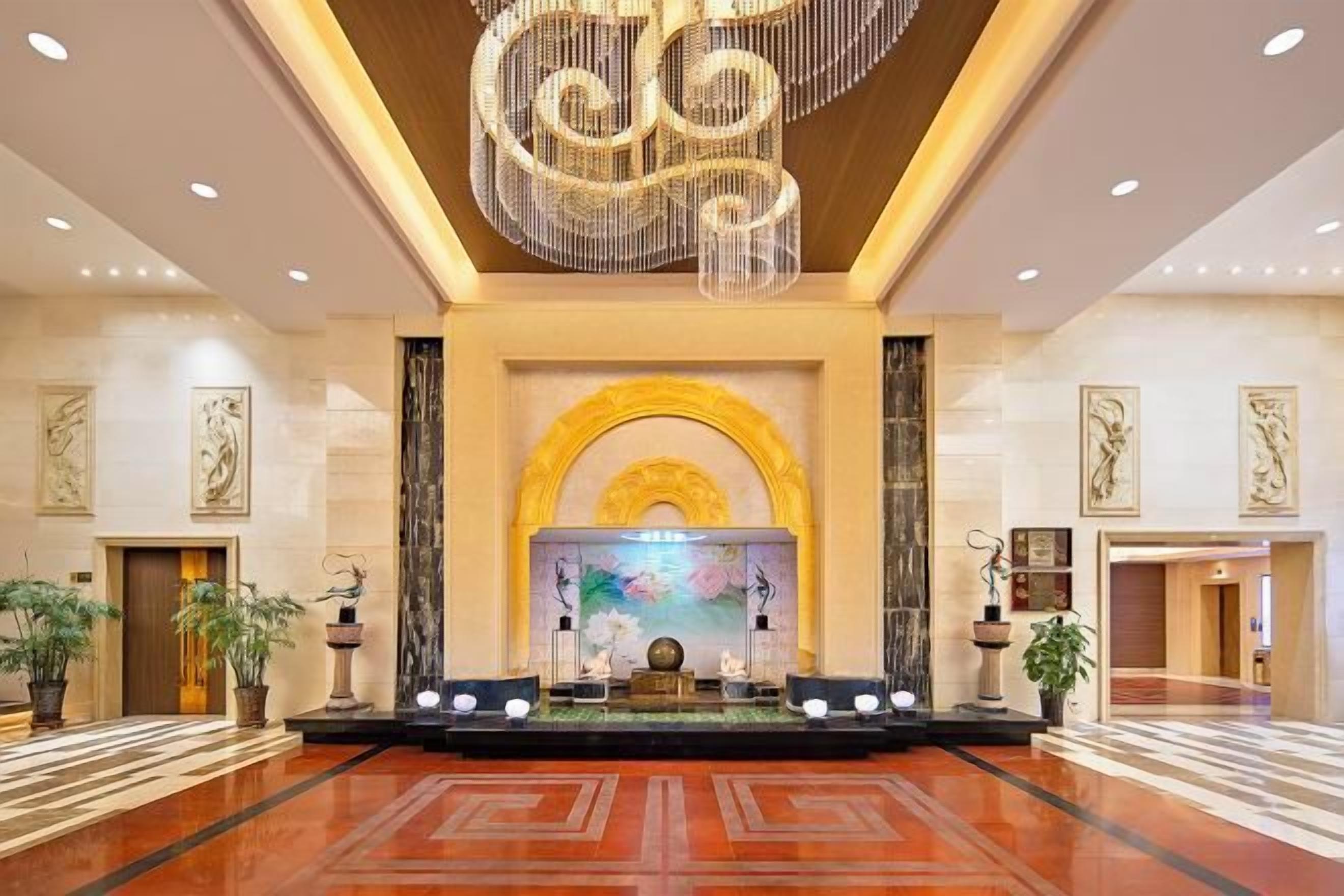 A spacious lobby with a grand chandelier, a central stage, and a large fountain.