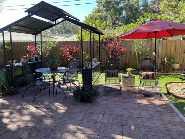 A patio with a covered seating area, a table, and chairs.