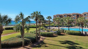 A resort with a swimming pool, palm trees, and a view of the ocean. - NEW KITCHEN! BeachFront, Bch Svc, pool, grill, kitchen, wifi (Miramar Beach)