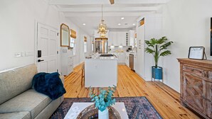 A modern kitchen with white cabinets, a central island, and a ceiling fan.
