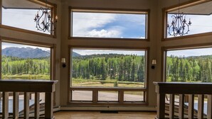 A room with large windows offering a view of a forest and mountains.