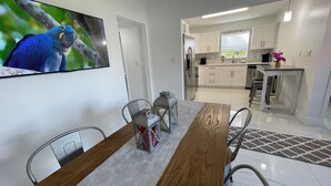 A modern kitchen with white cabinets, a stainless steel refrigerator, and a window with blinds. - Charming house in the heart of Wellington (Wellington)