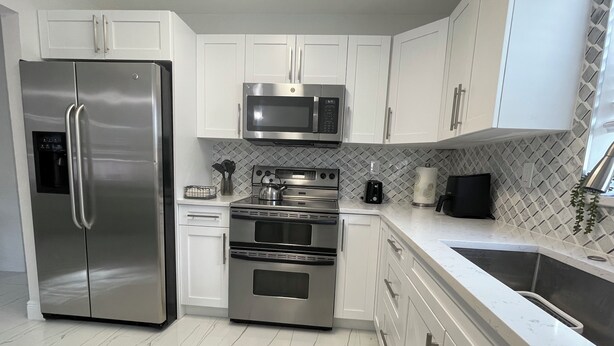 A modern kitchen with stainless steel appliances, white cabinets, and a tiled backsplash. - Charming house in the heart of Wellington (Wellington)