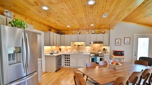 Una cocina moderna con techo de madera, electrodomésticos de acero inoxidable y una isla central con sillas.