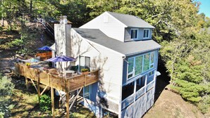 Una casa de dos pisos con un balcón, ventanas grandes y una chimenea.