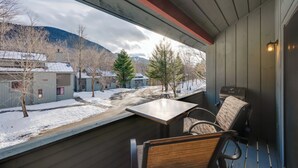 A balcony with a table and chairs, overlooking a snowy street and buildings. - Lincoln Condo w/ Balcony & View < 2 Mi to Loon Mtn (Lincoln)