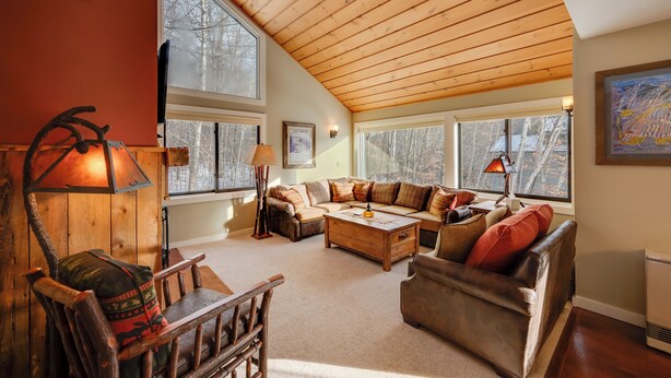 A cozy living room with a wooden ceiling, large windows, a sofa set, and a fireplace. - Lincoln Condo w/ Balcony & View < 2 Mi to Loon Mtn (Lincoln)