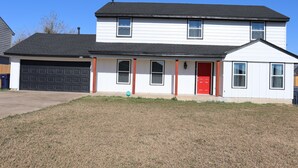 A two-story house with a garage, a red door, and a small porch. - Chisholm Creek by Top Golf 2 (Oklahoma City)