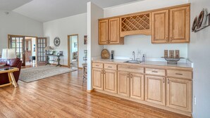 A spacious kitchen with wooden cabinets, a large island, and a dining area with a red sofa and table. - Beautiful Home with Breathtaking Views! (Nathrop)