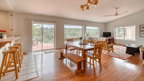 A spacious dining area with a wooden table and benches, large windows offering a view of the outdoors, and a ceiling fan. - Beautiful Home with Breathtaking Views! (Nathrop)