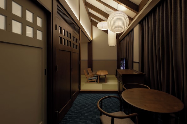 A hotel room with a traditional Japanese aesthetic, featuring tatami flooring, a low table with chairs, and a television. - Marufukuro (Kyoto)