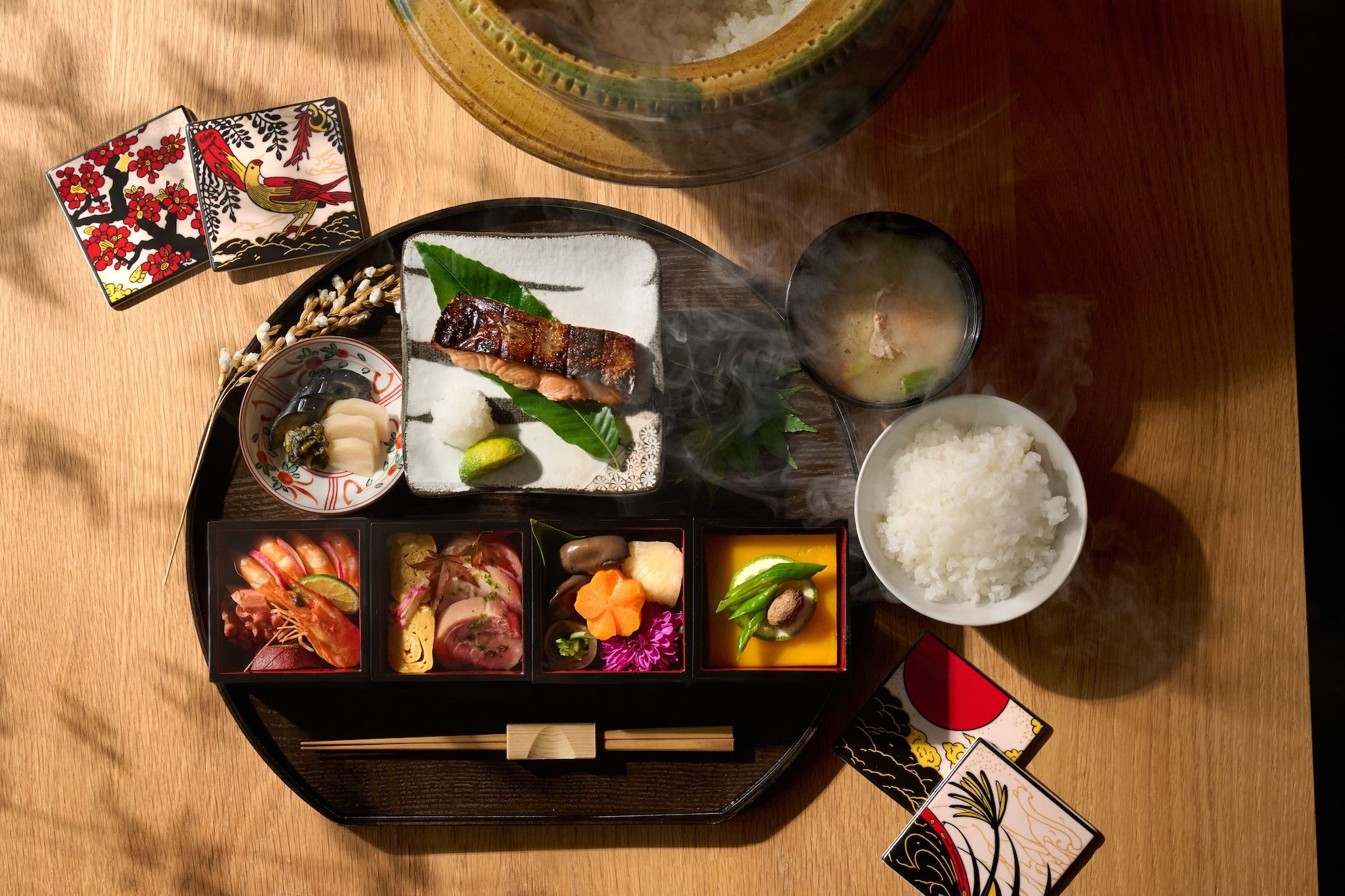 A traditional Japanese meal setup with various dishes, including sashimi, rice, and a hot pot, on a wooden table.