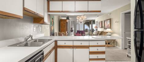 A modern kitchen with white cabinets, a built-in dishwasher, and a large island with a sink.