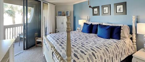 Une chambre à coucher avec un lit, un ventilateur de plafond, une table de chevet, une lampe et une vue sur l’extérieur.
