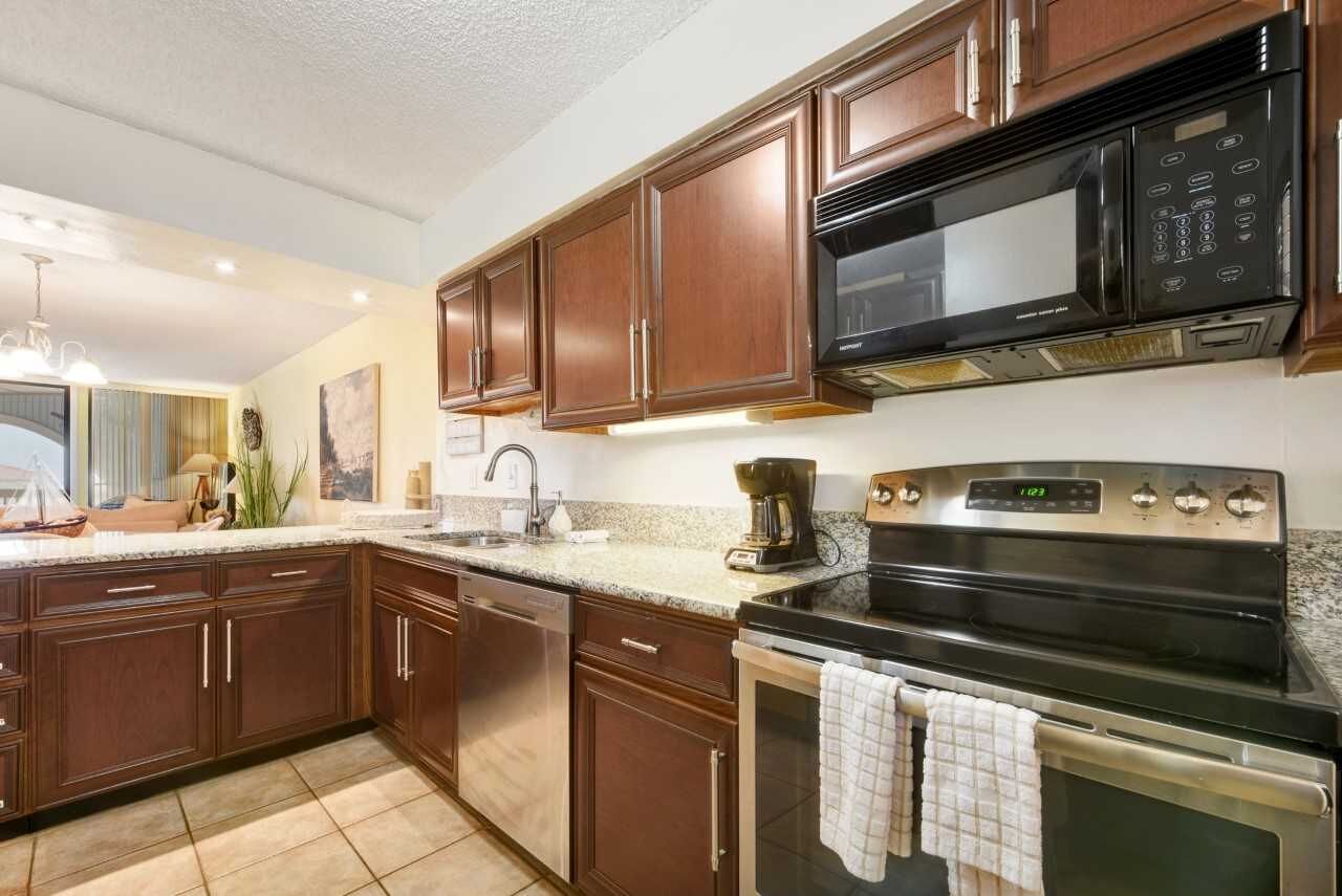 A kitchen with dark wooden cabinets, a stainless steel microwave, and a built-in oven.