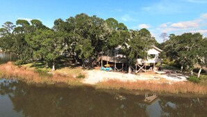 A lakeside property with a house on stilts, a dock, and a small docked boat.