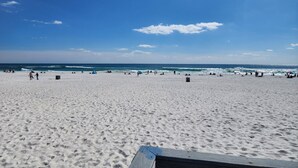 A beach with a clear sky, sandy shore, and a few people.