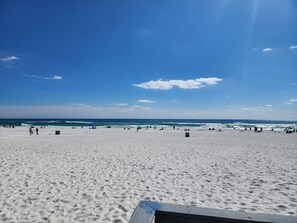 Ein Strand mit blauem Himmel, sandigem Ufer und einigen Personen.