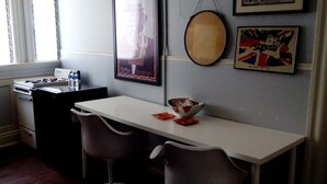 A kitchen with a white countertop, two grey bar stools, a stove, and a framed poster on the wall. - Historic Alvarado Terrace (Los Angeles)