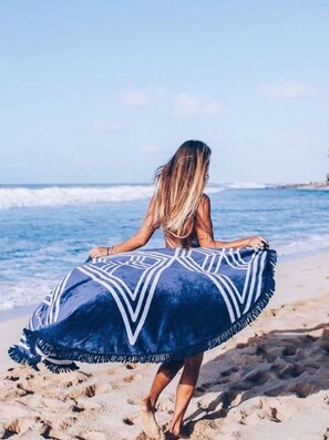 A person on a beach holding a blue patterned blanket. - Historic Alvarado Terrace (Los Angeles)