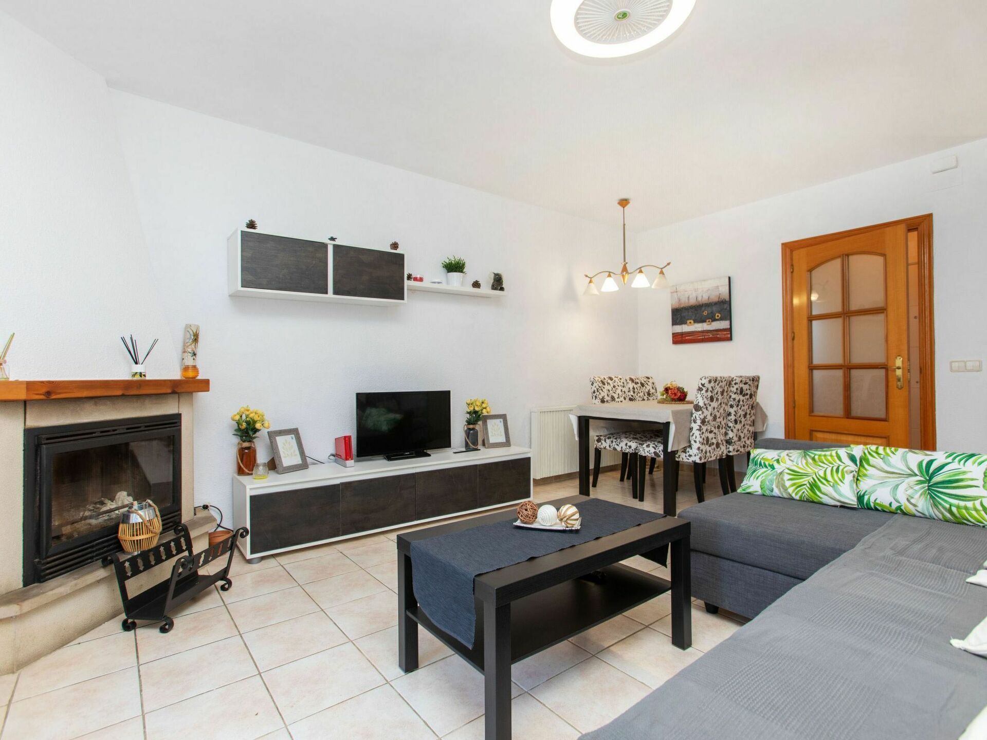 Uma sala de estar moderna com lareira, televisão, área de jantar e sofá.