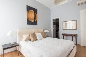 A bedroom with a bed, bedside tables, a wall-mounted artwork, and a door leading to a closet.