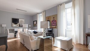 Ein modernes Wohnzimmer mit einer Couch, einem Glastisch, einem Fernseher und Kunstwerken an der Wand.