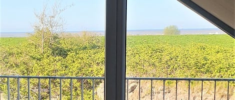 A balcony with two chairs, a view of a green field, and a clear sky.