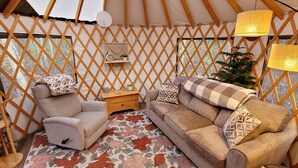 A cozy interior with a sofa, armchair, and a small table with a lamp. - Hideaway Glamping Yurt  (Bellingham)