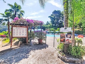 Un espace piscine agrémenté d’un panneau d’affichage, d’un bar au bord de la piscine et de chaises longues.