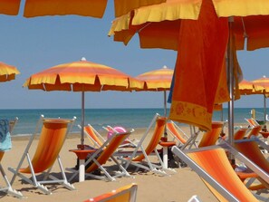 Een strand met rijen ligbedden en parasols.