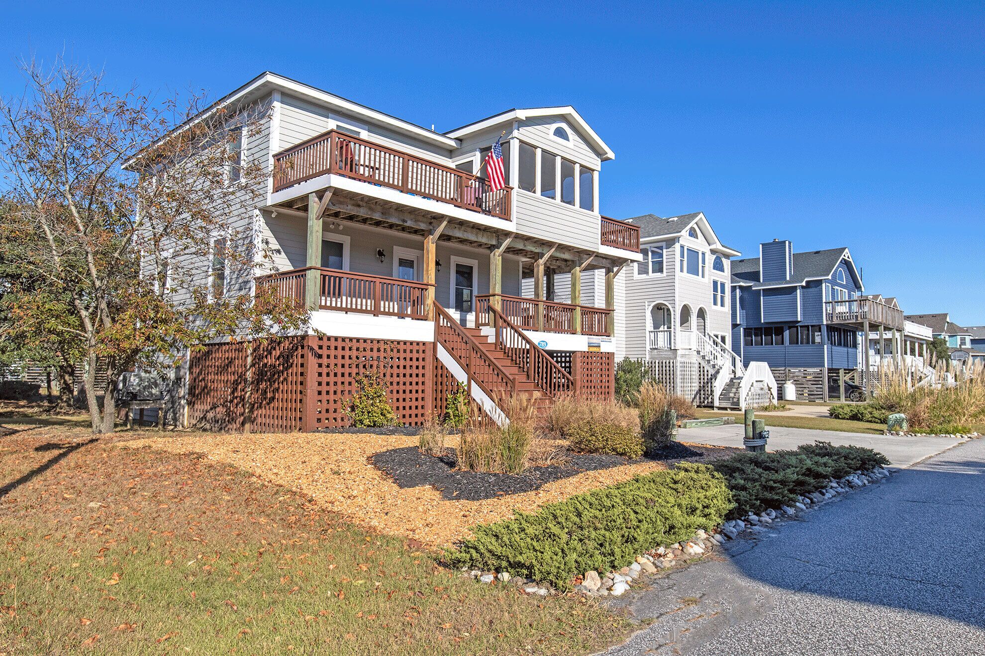 A two-story house with a balcony, a flag, and a driveway.