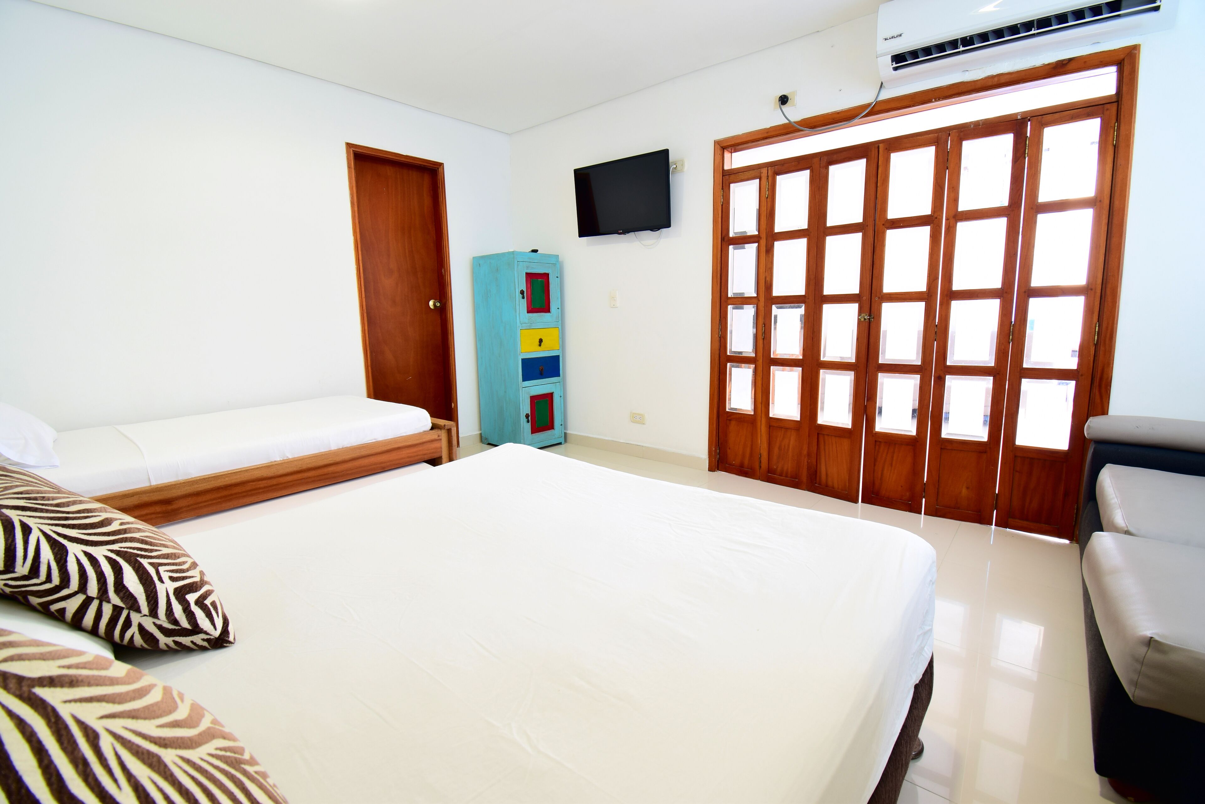 A hotel room with a large bed, a wardrobe, a television, and a sliding door.