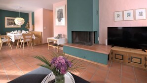 A living room with a fireplace, a dining area, and a TV. - Chesa Maurus A5 by Interhome (St. Moritz)