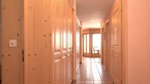 A hallway with wooden doors and a tiled floor. - Chesa Maurus A5 by Interhome (St. Moritz)
