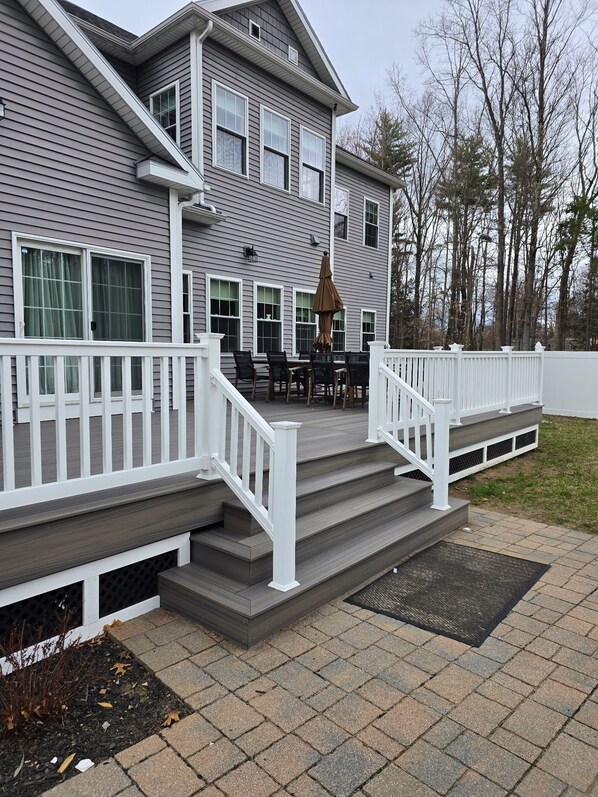 A two-story house with a covered patio area featuring a table and chairs.