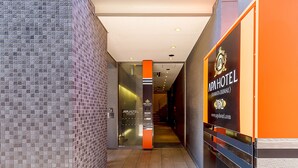 A hallway with tiled walls, a glass door, and an orange sign for APA HOTEL. - APA Hotel Kamata Ekimae (Tokyo)