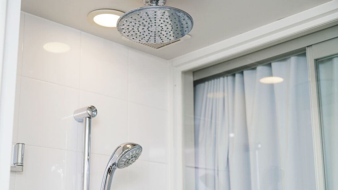 Un bany modern amb dutxa, vàter i finestra amb cortines.