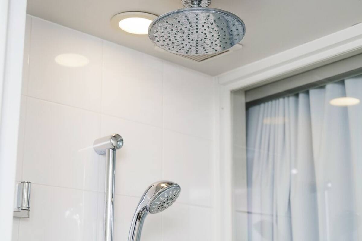 A modern bathroom with a shower, a toilet, and a window with curtains.