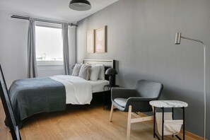 A modern hotel room with a bed, a chair, a small table, and a window with curtains. - Newly renovated Mariahilf 1BR, short walk to Metro U4 & U3, by Blueground (Vienna)