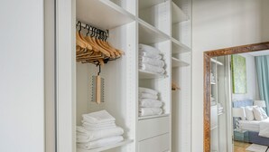 A well-organized closet with hanging clothes, shelves with folded towels, and a mirror. - Spacious 2BR + Office near Stephansplatz & Kohlmarkt, by Blueground (Vienna)