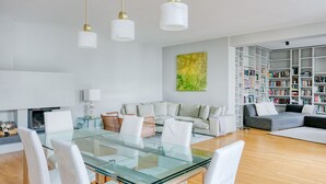 A modern living room with a glass dining table, white sofas, and a bookshelf filled with books. - Spacious 2BR + Office near Stephansplatz & Kohlmarkt, by Blueground (Vienna)