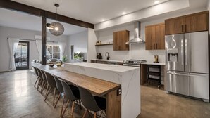 A modern kitchen with a central island, wooden cabinets, stainless steel appliances, and a dining area with chairs. - Silo at Hara Homes Luxury Stay (Leavenworth)