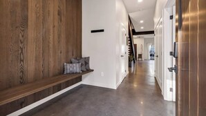 A modern hallway with a wooden accent wall, a bench with cushions, and a metallic door. - Silo at Hara Homes Luxury Stay (Leavenworth)