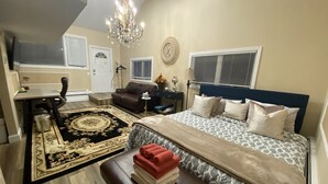 Un dormitorio con cama, escritorio, silla, sofá, candelabro y ventana.