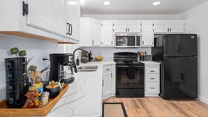 Una cocina moderna con gabinetes blancos, un refrigerador negro, una estufa y un microondas.