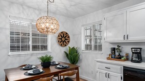 Una cocina moderna con armarios blancos, una mesa de comedor de madera y una lámpara colgante.
