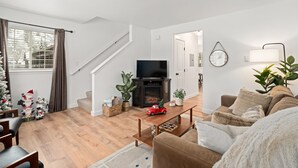 Una sala de estar moderna con chimenea, suelo de madera, un sofá y un televisor.